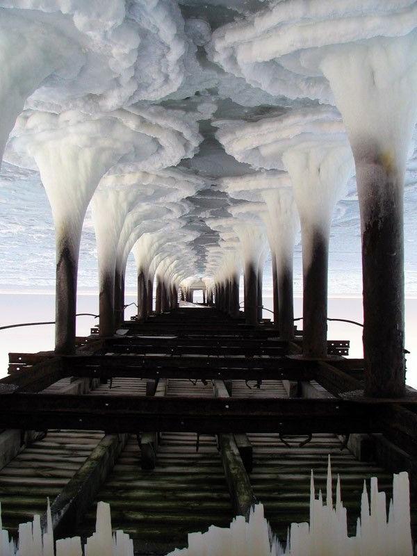 Une photo retournée des piliers d'un ponton d'un lac gelé.
