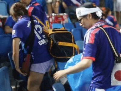 Des supporters japonais nettoient les tribune après le match.
